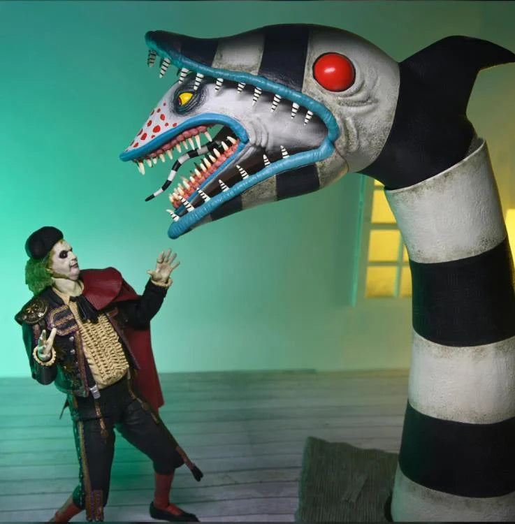 Primer plano de Beetlejuice con expresión de burla, luciendo su traje de luces amarillo y capa de tela roja.